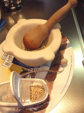 pestare aglio e pinoli con il mortaio