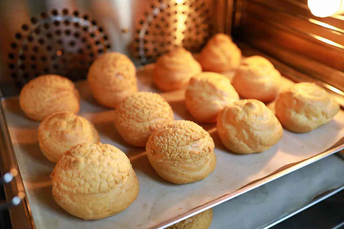 Teglia con bignè in pasta choux durante la cottura in forno