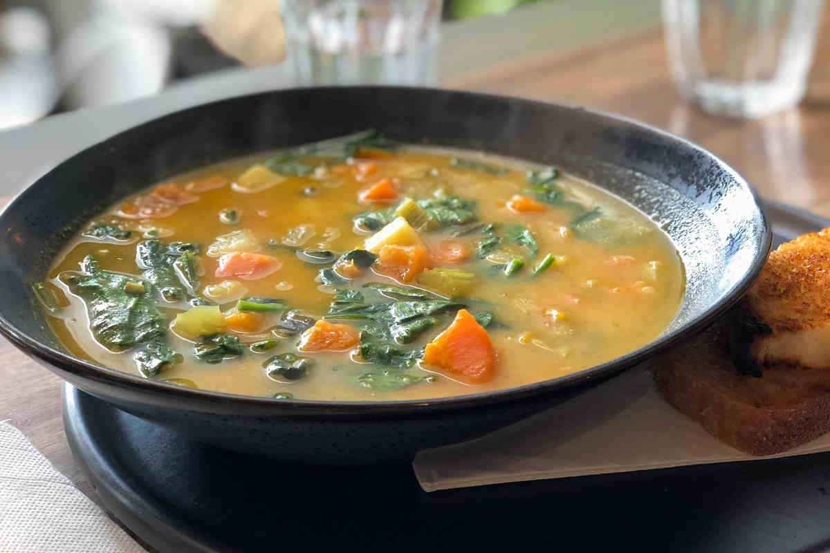 piatto fondo nero con zuppa di verdure miste in brodo