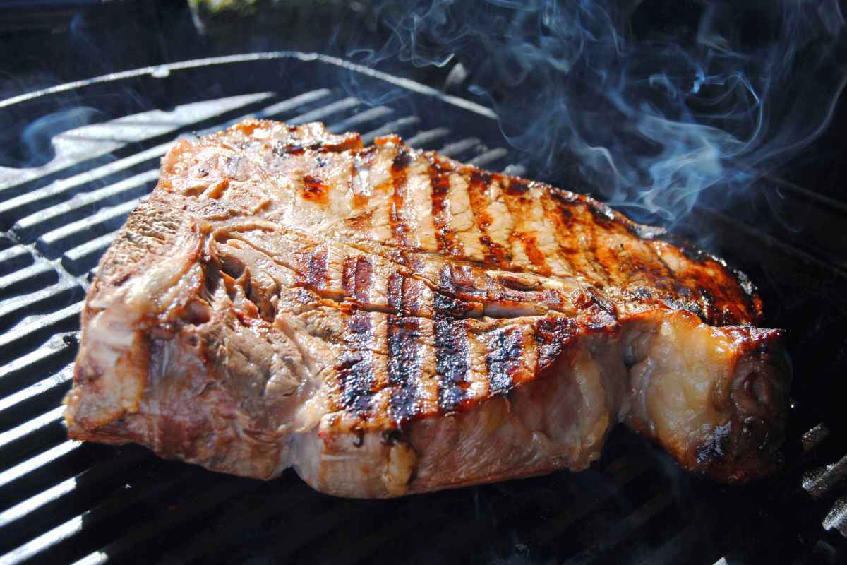 teglia griglia di ghisa con fetta di bistecca alla fiorentina in cottura