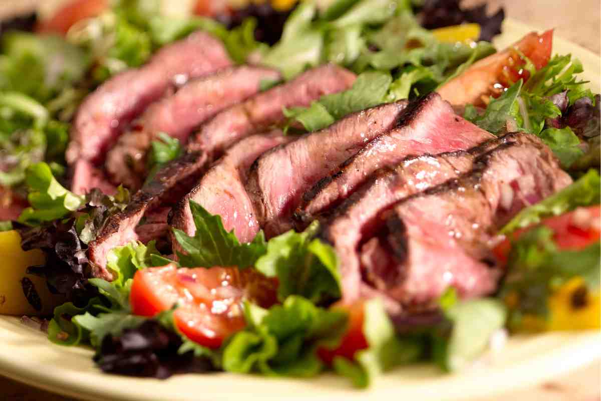 Bistecche di manzo tagliate a fettine in mezzo all'insalata