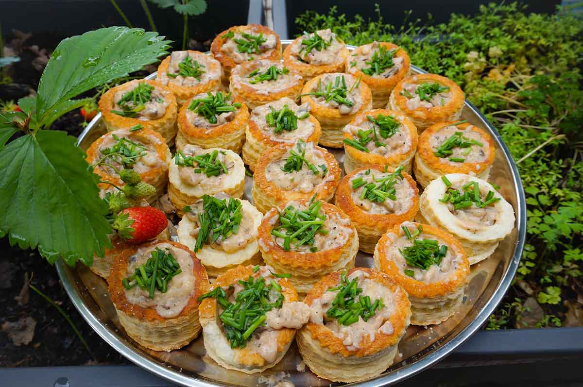 Vassoio con dei vol-au-vent ripieni di insalata russa e decorati con erbe aromatiche