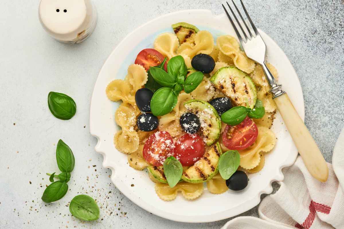 piatto di pasta fredda con zucchine, pomodorini e olive