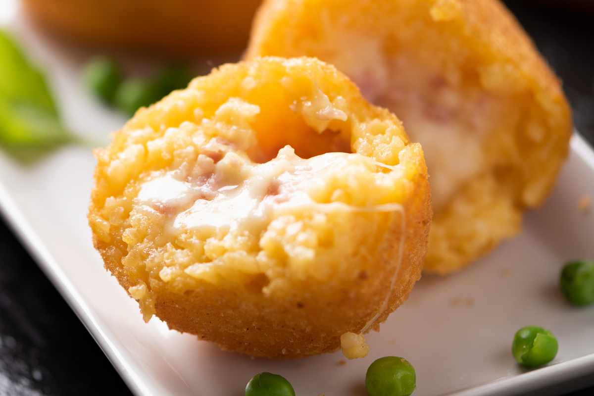 palline di riso con acciughe e formaggio filante aperte a metà in un piatto