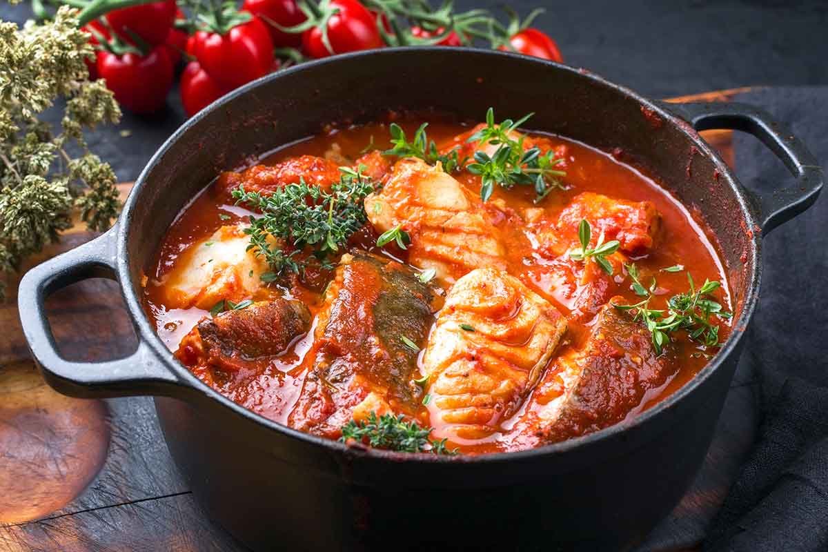 Tegamino nero con all'interno un merluzzo con pomodoro