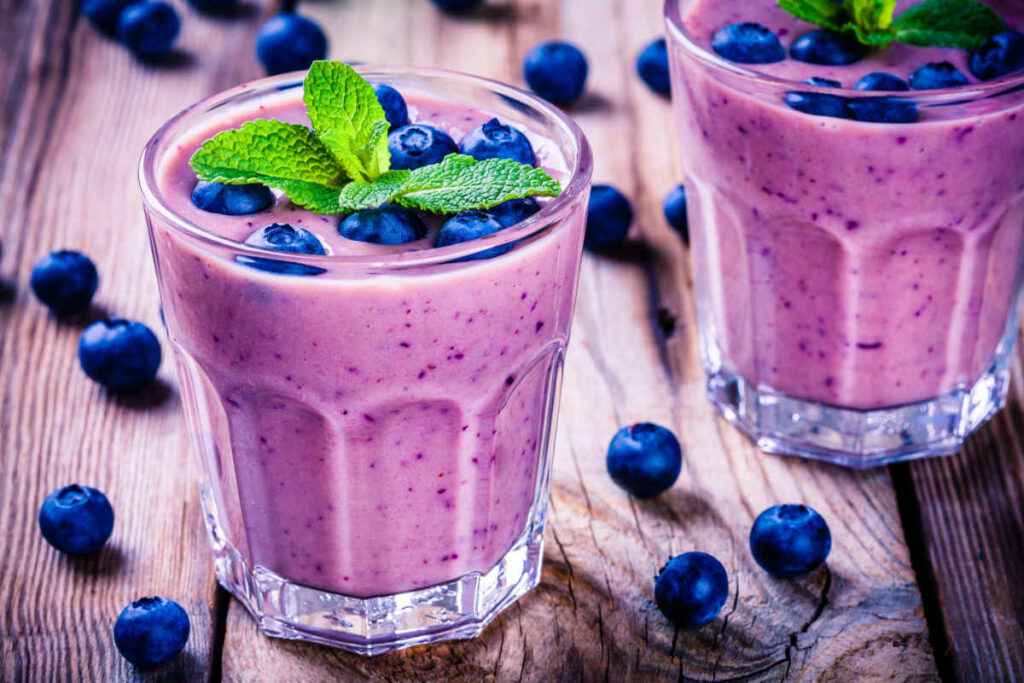 2 bicchieri con smoothie viola con banane e mirtilli