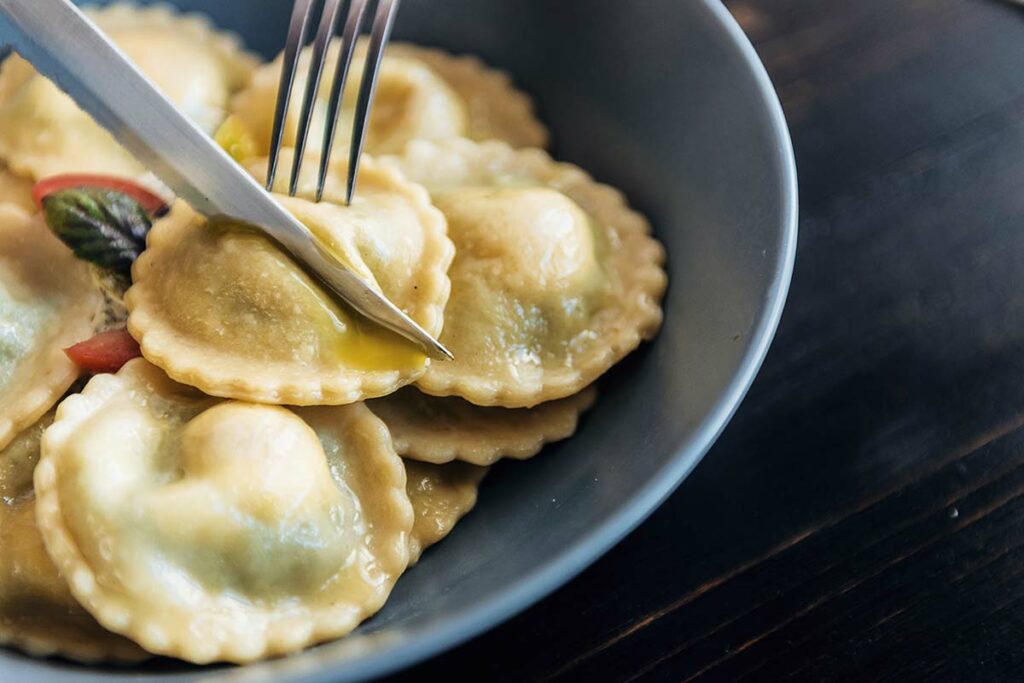 Piatto di ravioli con una forchetta che fa fuoriuscire il tuorlo liquido