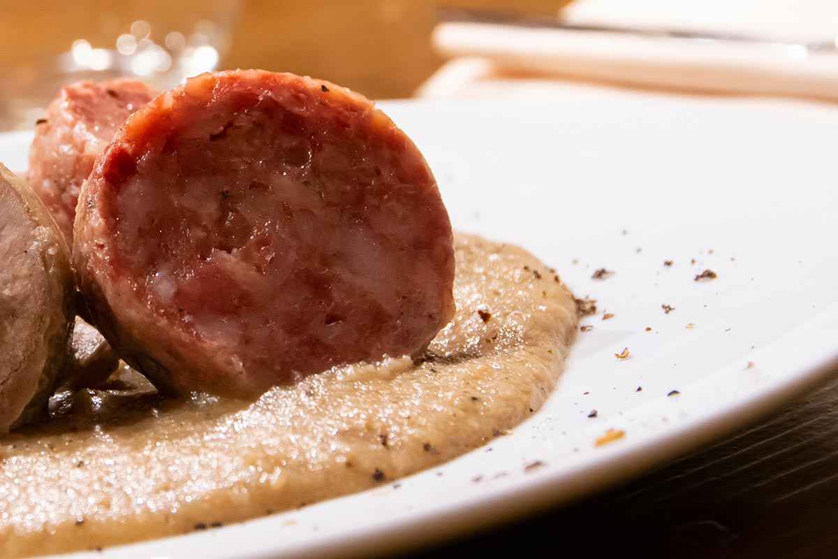 Piatto con fetta di cotechino su crema di fagioli vellutata