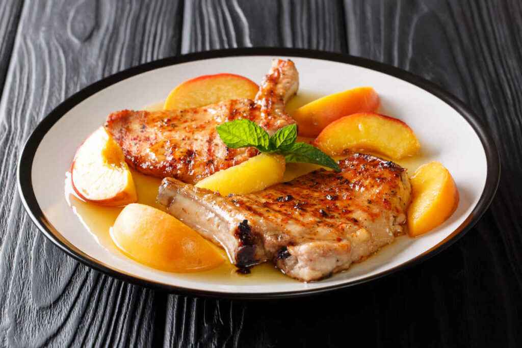 piatto con bistecche di carne condite con pesche e salsa per ricette salate con frutta