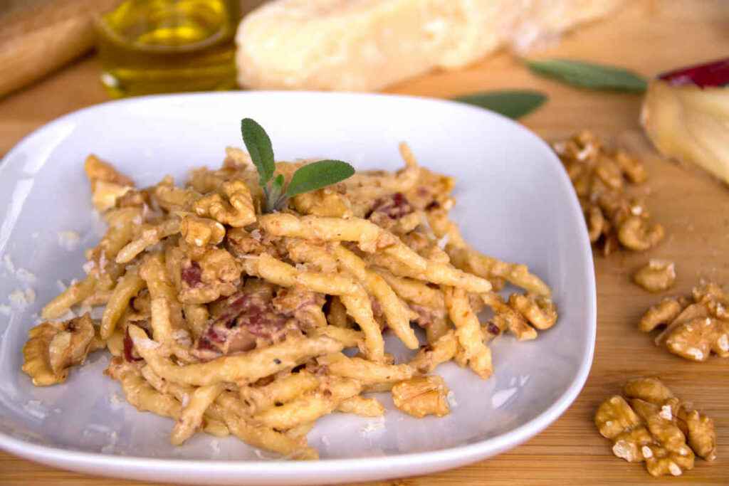 piatto con porzione di pasta al pesto di noci e pancetta