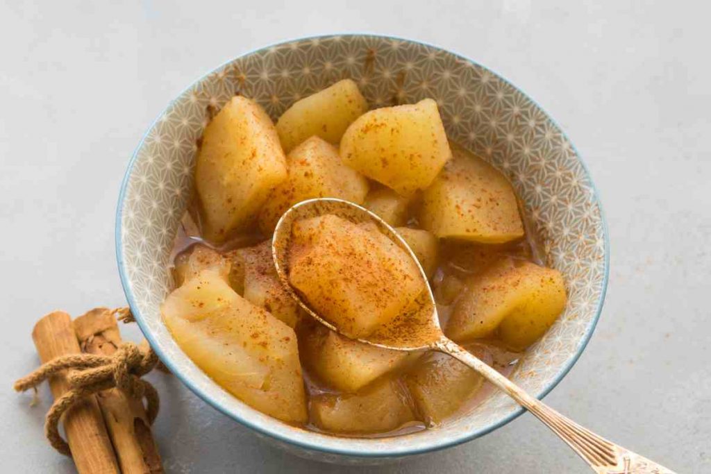 mele cotte spolverate con cannella in una ciotola