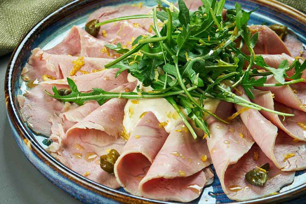 Piatto con fette di vitello tonnato e rucola