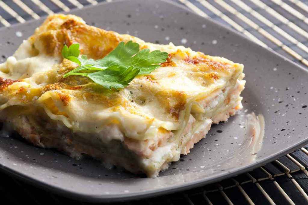 Piatto di lasagne con besciamella, salmone affumicato e mozzarella