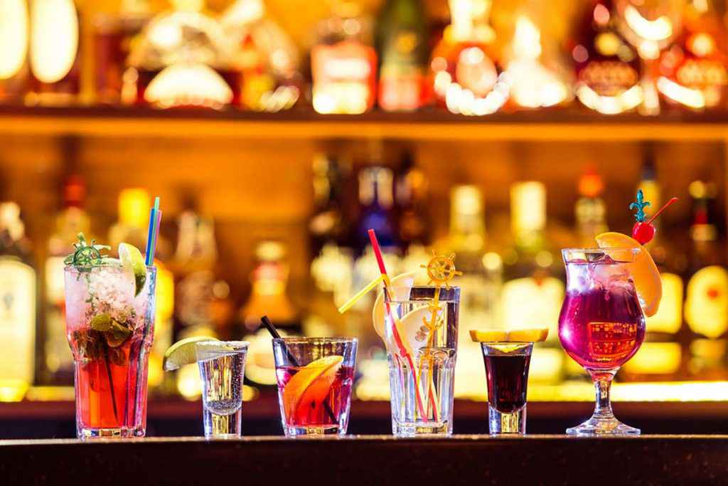 Bancone da bar con coktail alcolici colorati in bicchieri differenti