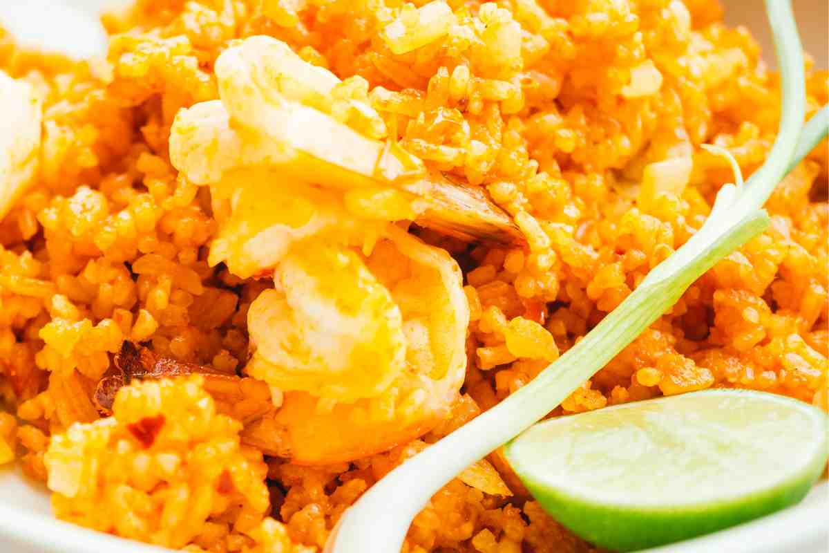 Risotto curry e gamberetti in piatto guarnito con fetta di lime