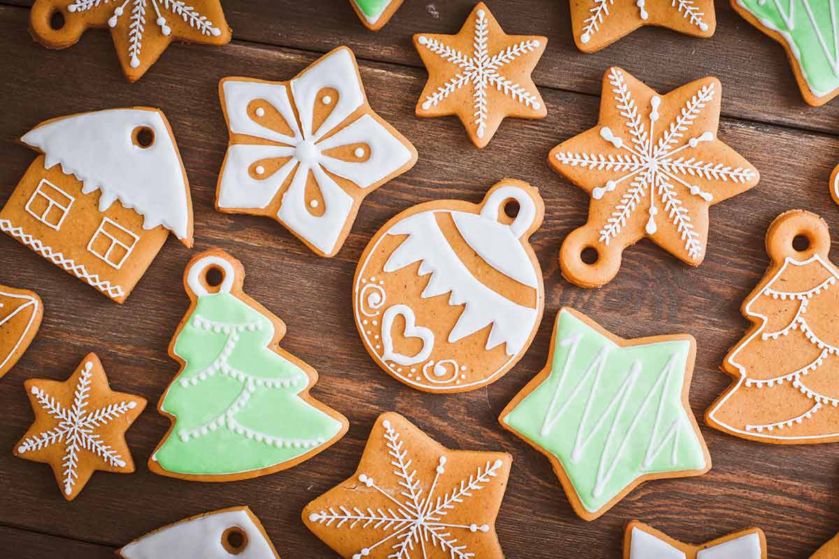 Tavola in legno con sopra tanti biscotti da appendere all'albero di natale come decorazione natalizia