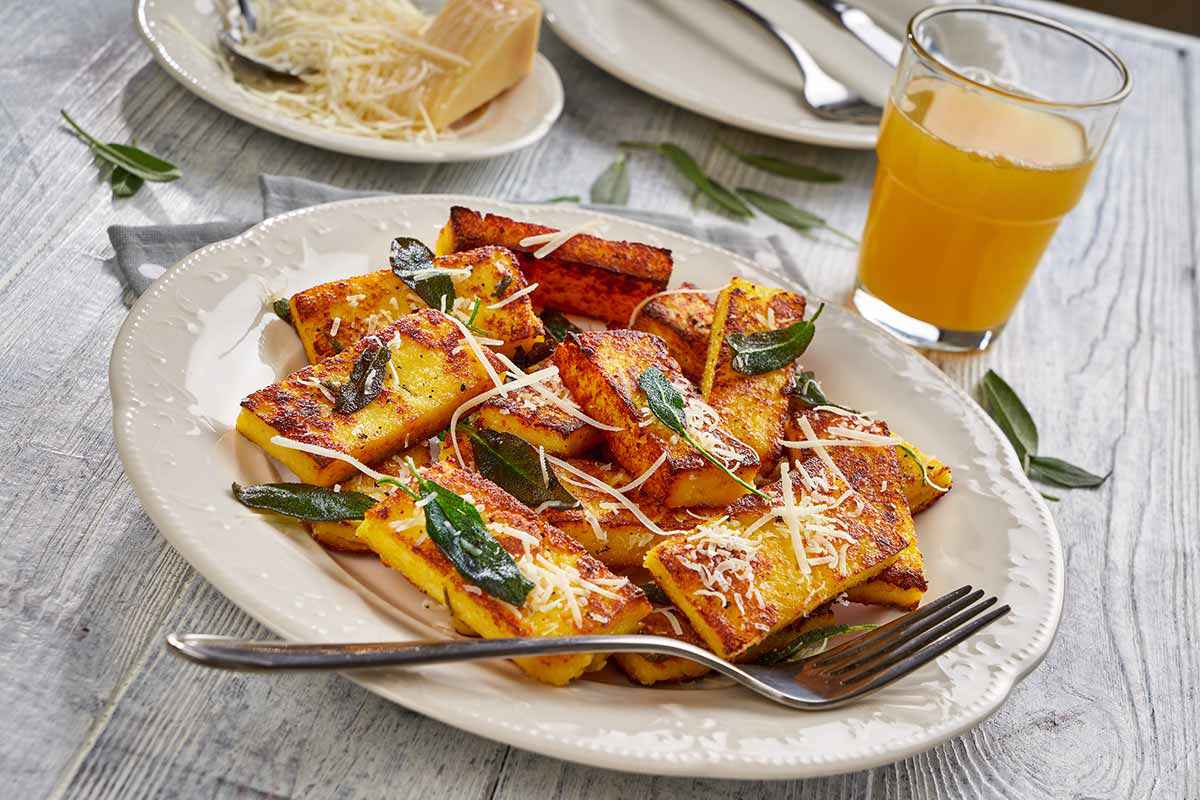 Piatto appoggiato su di un tavolo di legno con della polenta fritta al suo interno