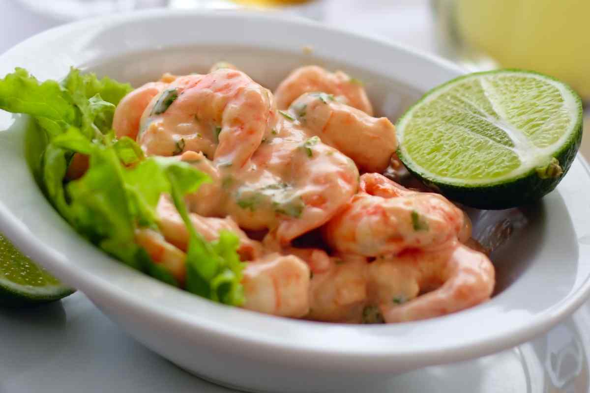 ciotola con cocktail di gamberetti, insalata e metà lime