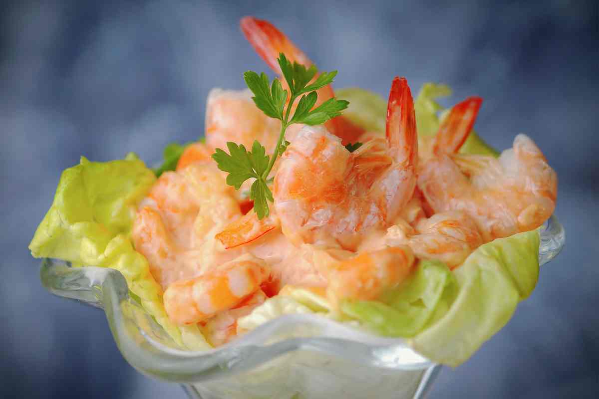 una coppa con dentro delle foglie di lattuga e il Cocktail di scampi e mazzancolle
