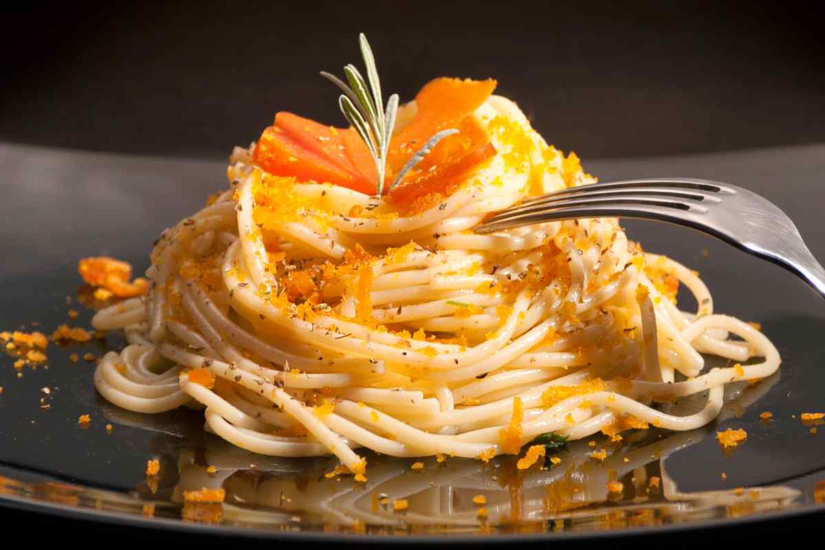 Spaghetti con la bottarga, limone e origano in un piatto nero
