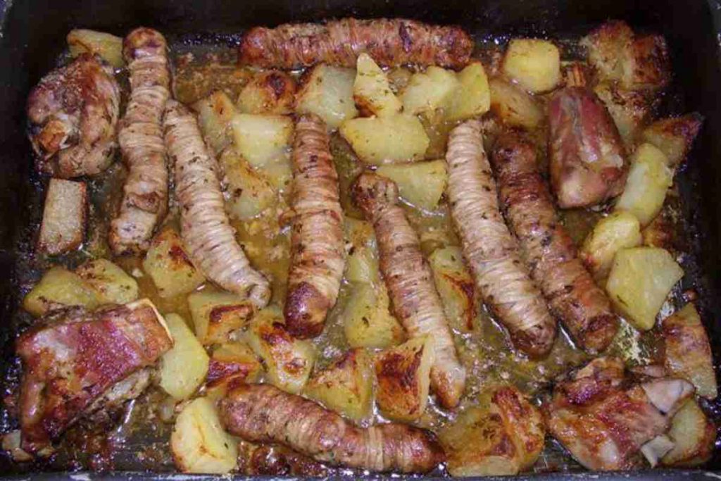Torcinelli o gnumeriedde con patate al forno in una teglia