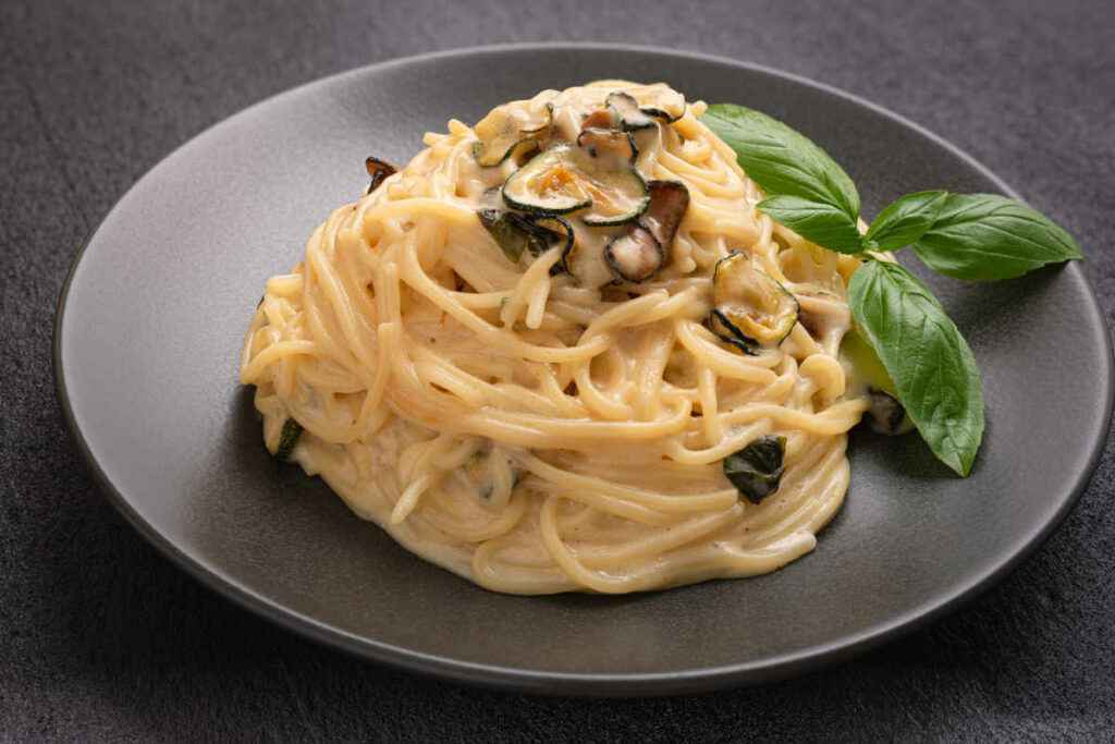 piatto nero con porzione di spaghetti alla nerano