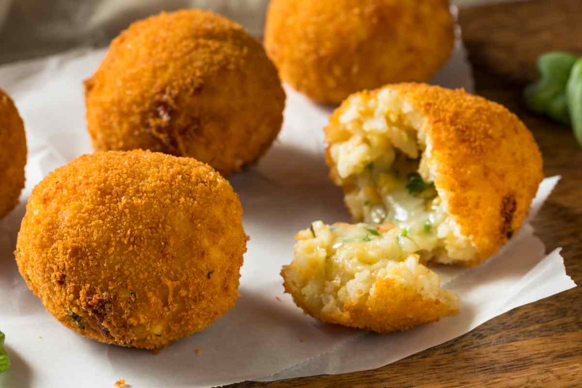 quattro arancini di riso con zucchine e speck su un tavolo