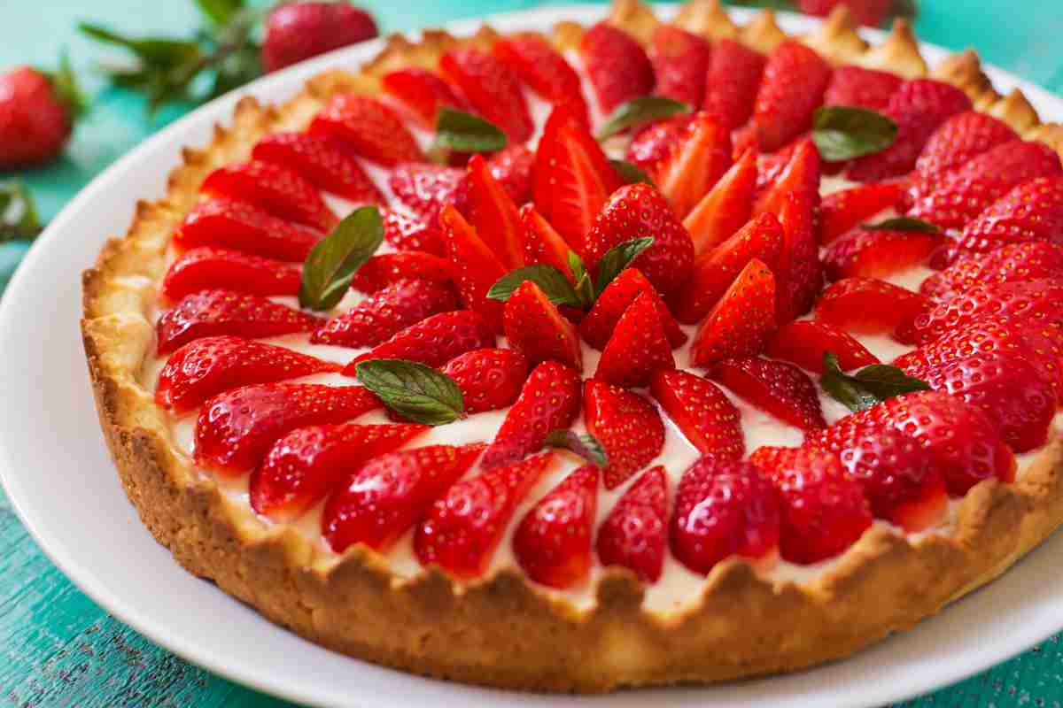 Crostata fragole e mascarpone in un vassoio decorata con foglioline di menta