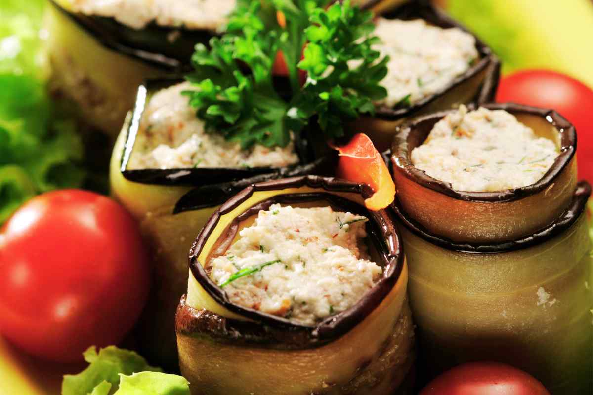 Involtini di melanzane con tonno e ricotta in un piatto guarnito con pomodorini