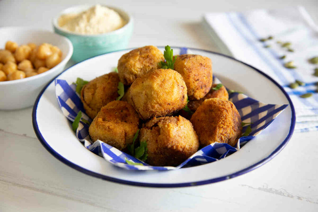 piatto bianco con bordo blu pieno di polpette di ceci appena cotte