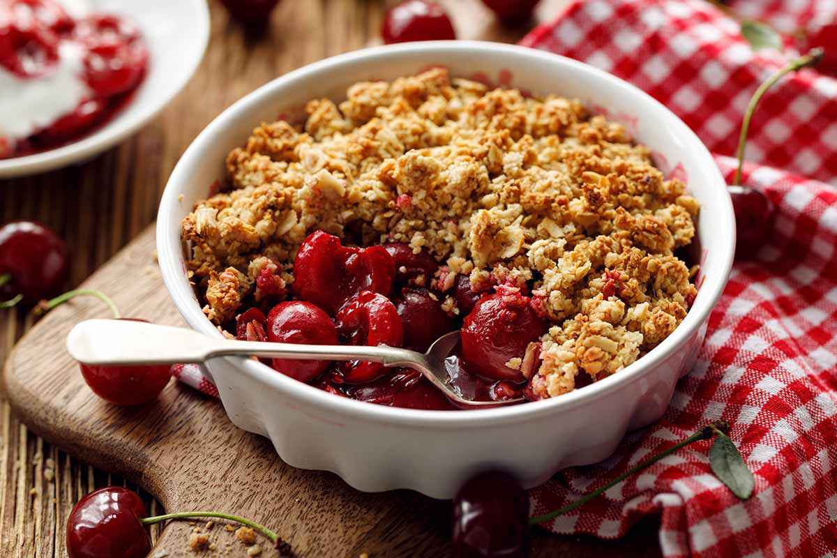 Terrina su tavolo di legno con all'interno un crumble di ciliegie