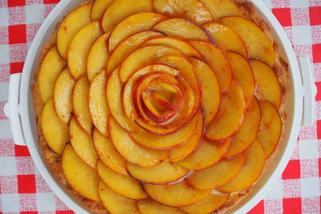 teglia tonda con torta con marmellata di pesche e frutta fresca