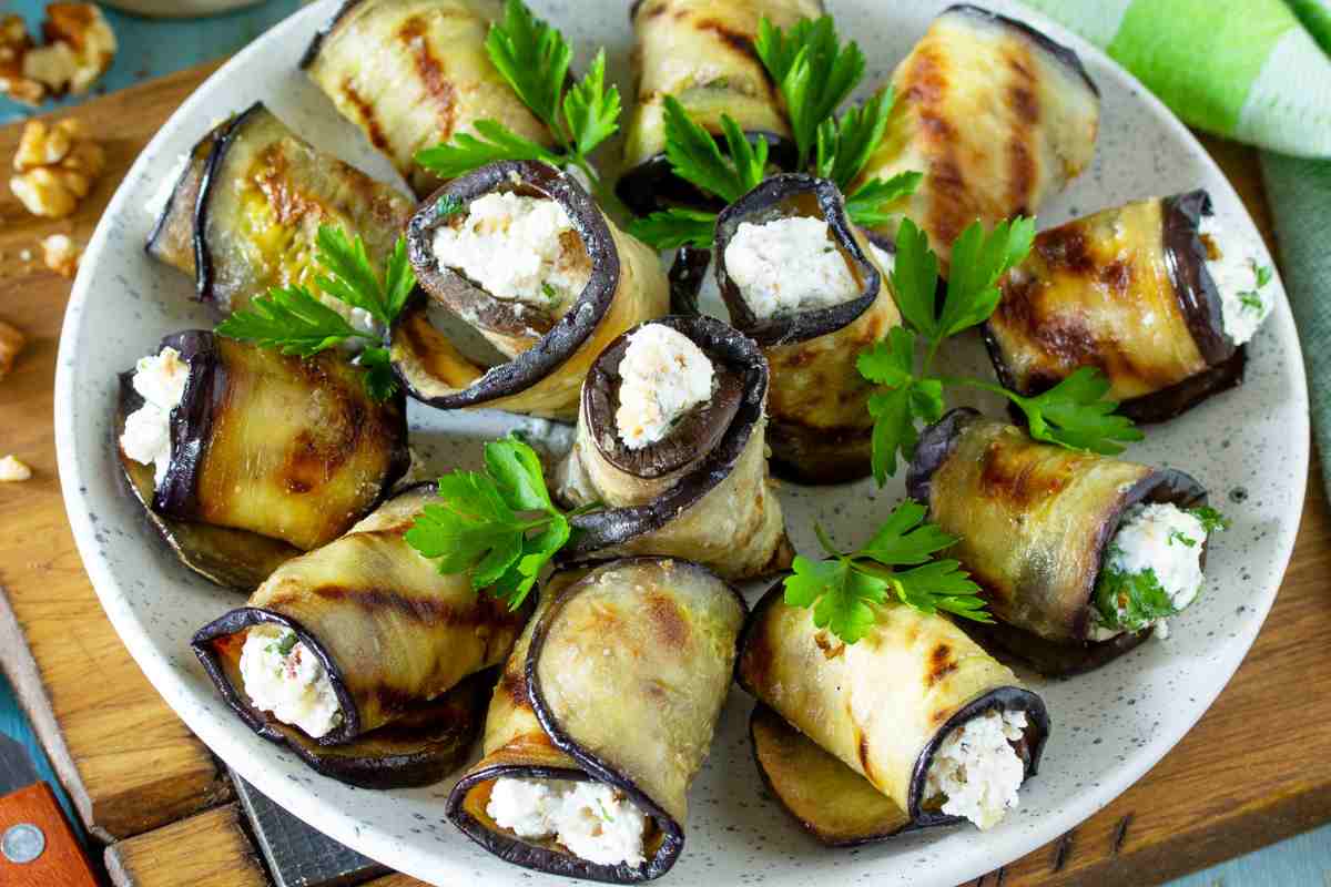 Involtini di melanzane e ricotta disposti a raggiera in un piatto