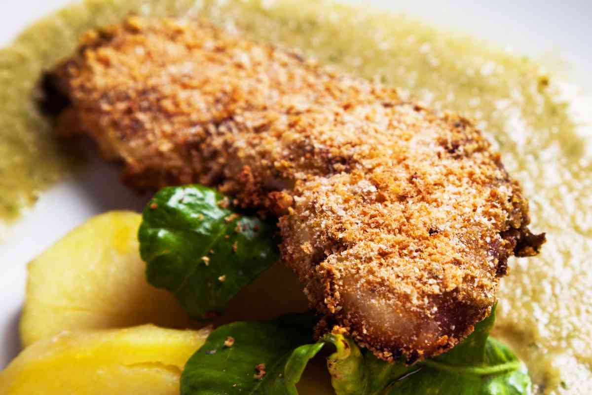 fetta di pesce spada croccante in un piatto con contorno di patate