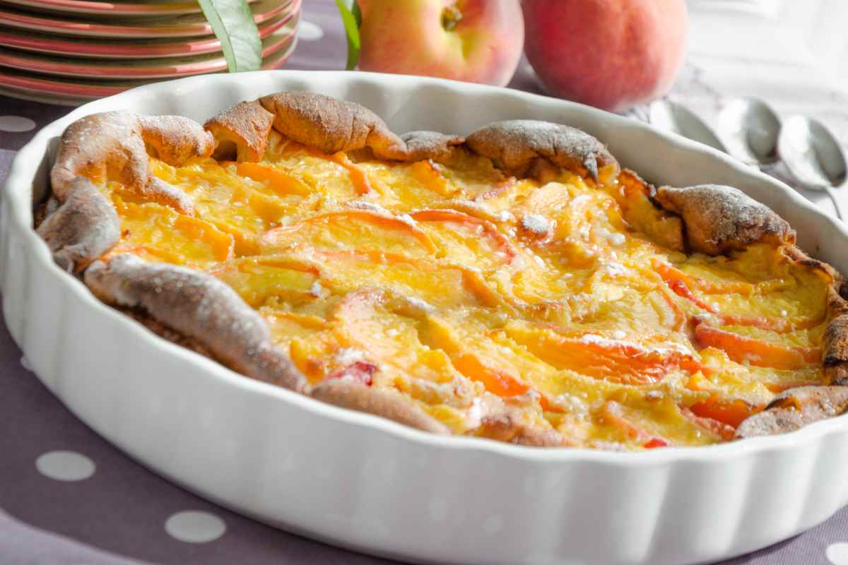 Clafoutis di pesche in una pirofila bianca tonda