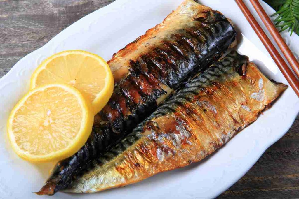 Sgombri grigliati in un piatto con fette di limone