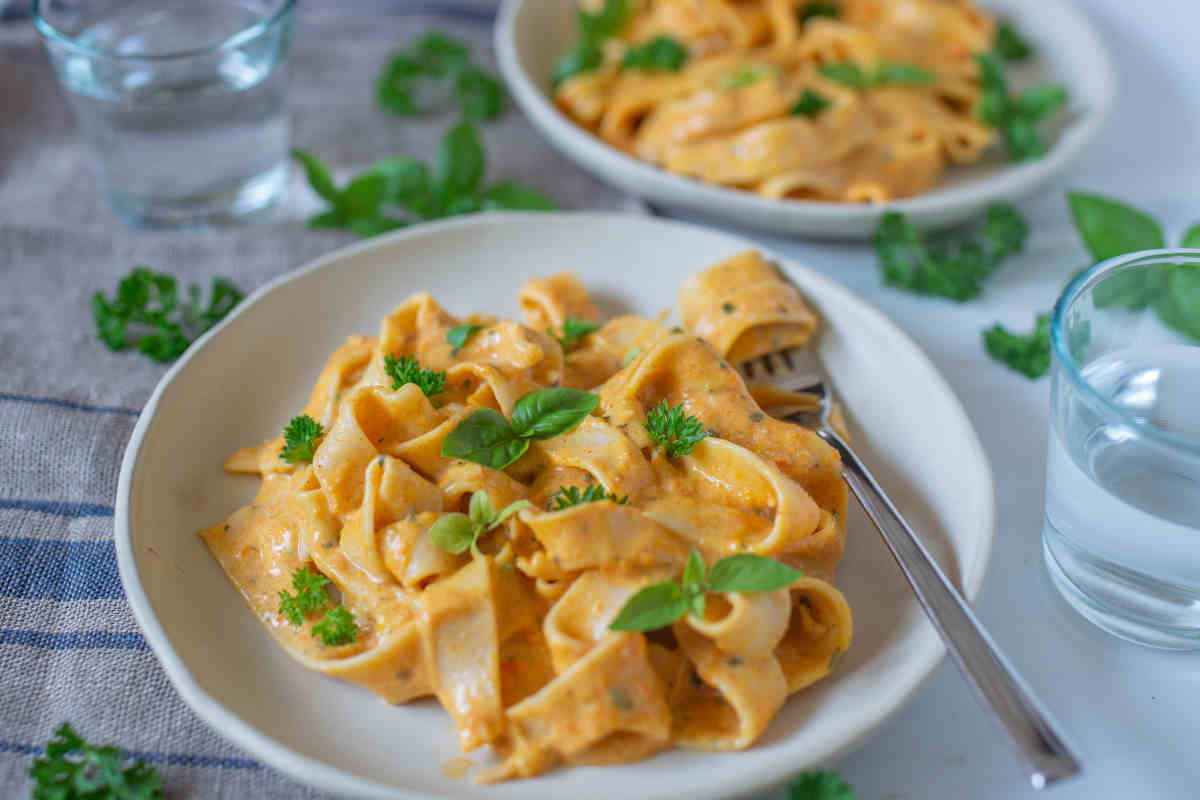 piatto piano con ricca porzione di tagliatelle con condimento di zucca e curry