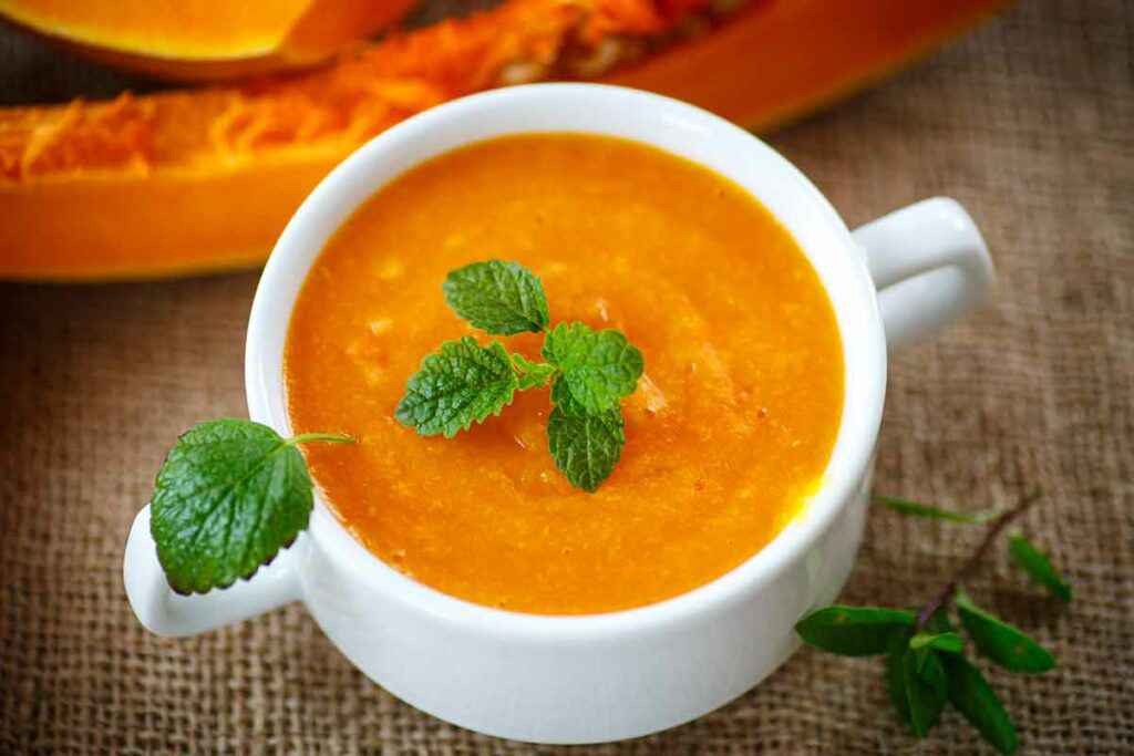 Ciotola con zuppa di zucca decorata con delle foglioline di menta, una delle ricette per rimettersi in forma