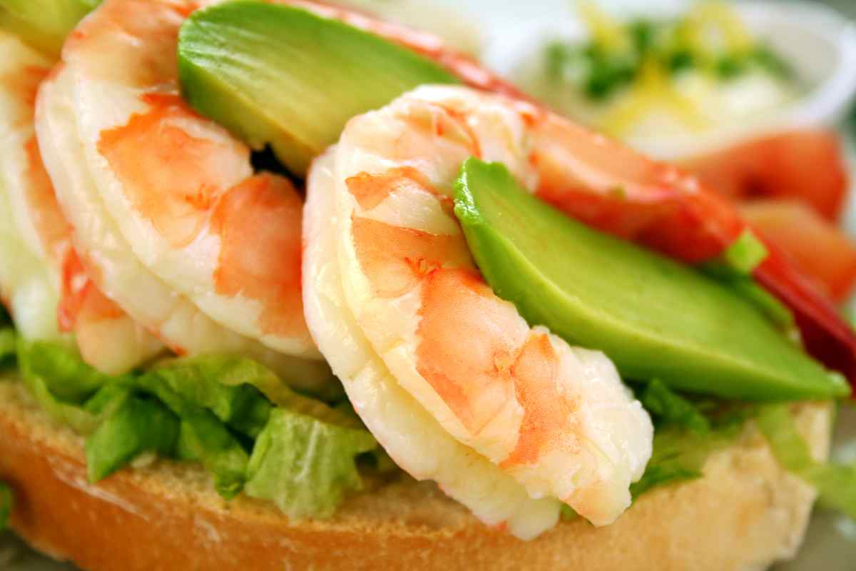gamberi alternati a fette di avocado su una bruschetta in un piatto