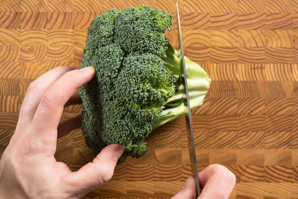 pulire e tagliare i broccoli su un tagliere di legno