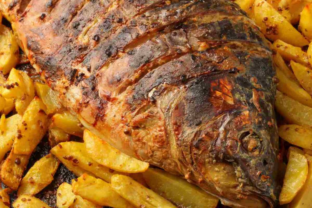 Carpa al forno su un letto di patate arrostite