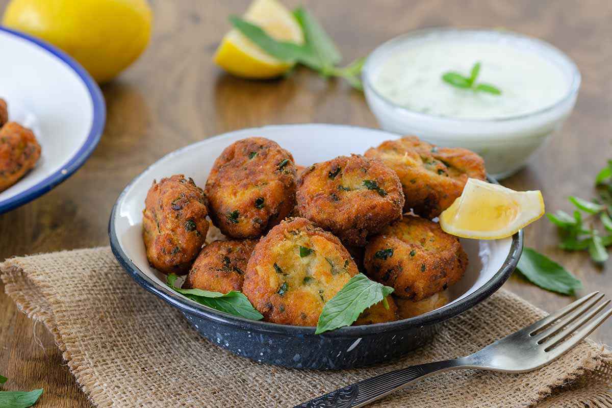 Piatto con polpette fritte con zucchine e ricotta e fetta di limone