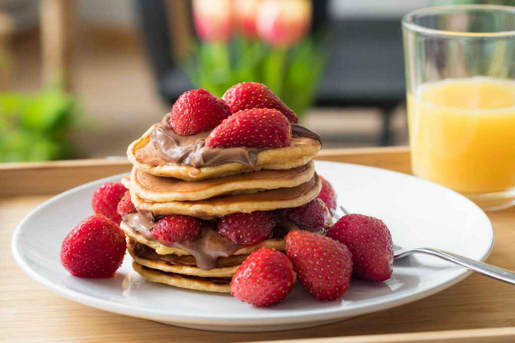 pancake alla nutella e fragole su piatto bianco