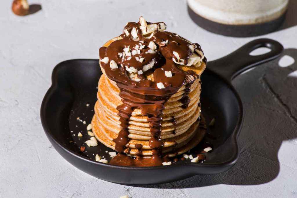 torre di pancake alla nutella e banana a fette con nocciole tritate