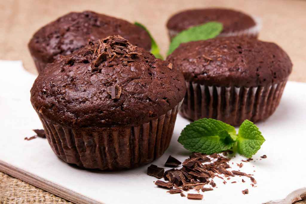 Muffin al cioccolato senza burro decorato con scaglie di cioccolato e foglia di menta