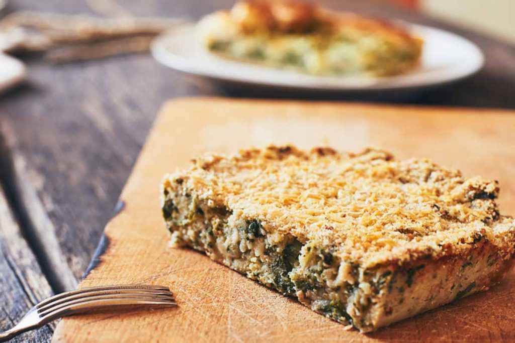 Fetta di gateau di patate e spinaci su di un tagliere