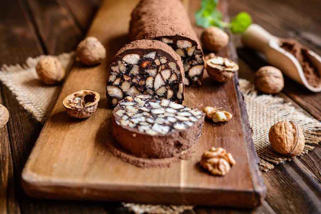 Tagliere di legno con rotoli dolci o salame di cioccolato a fette