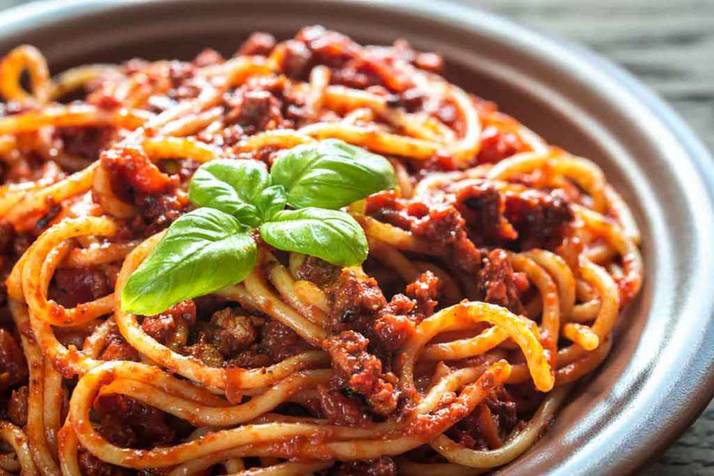 Piatto di spaghetti con ragù di carne alla bolognese e basilico