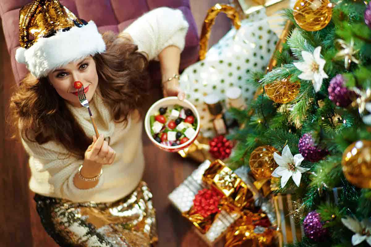 Donna con piatto light davanti a un albero di Natale