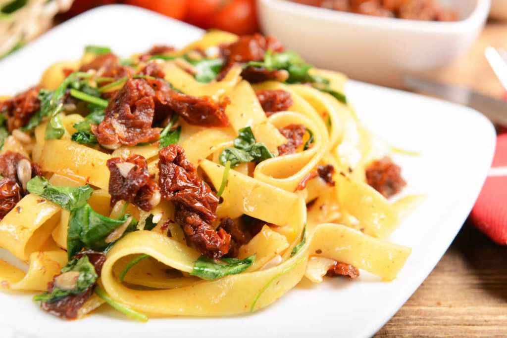 piatto di pasta con rucola e pomodori secchi